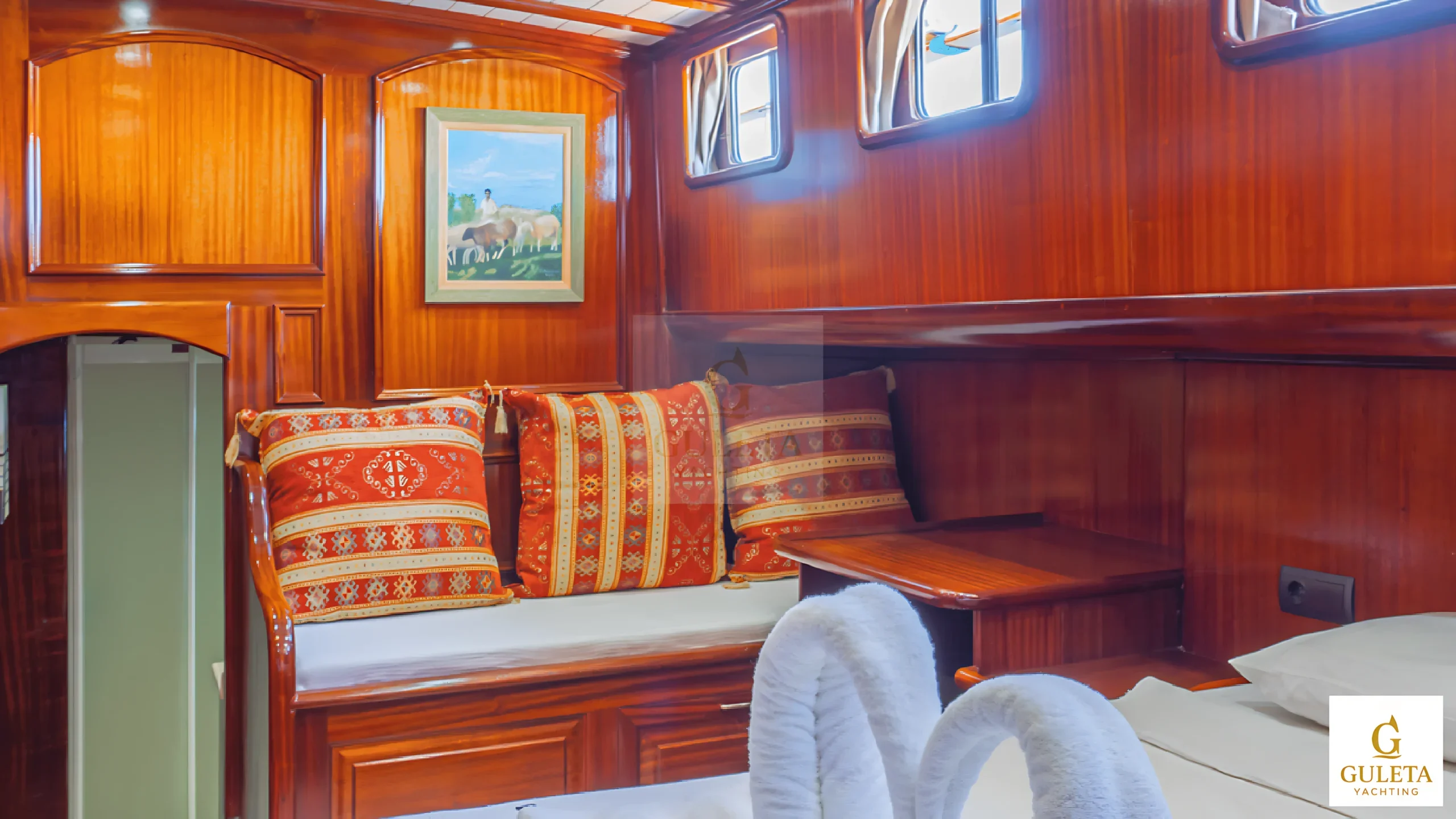Another view of Avrasya Gulet’s cabin lounge area with padded seating and wooden surfaces.