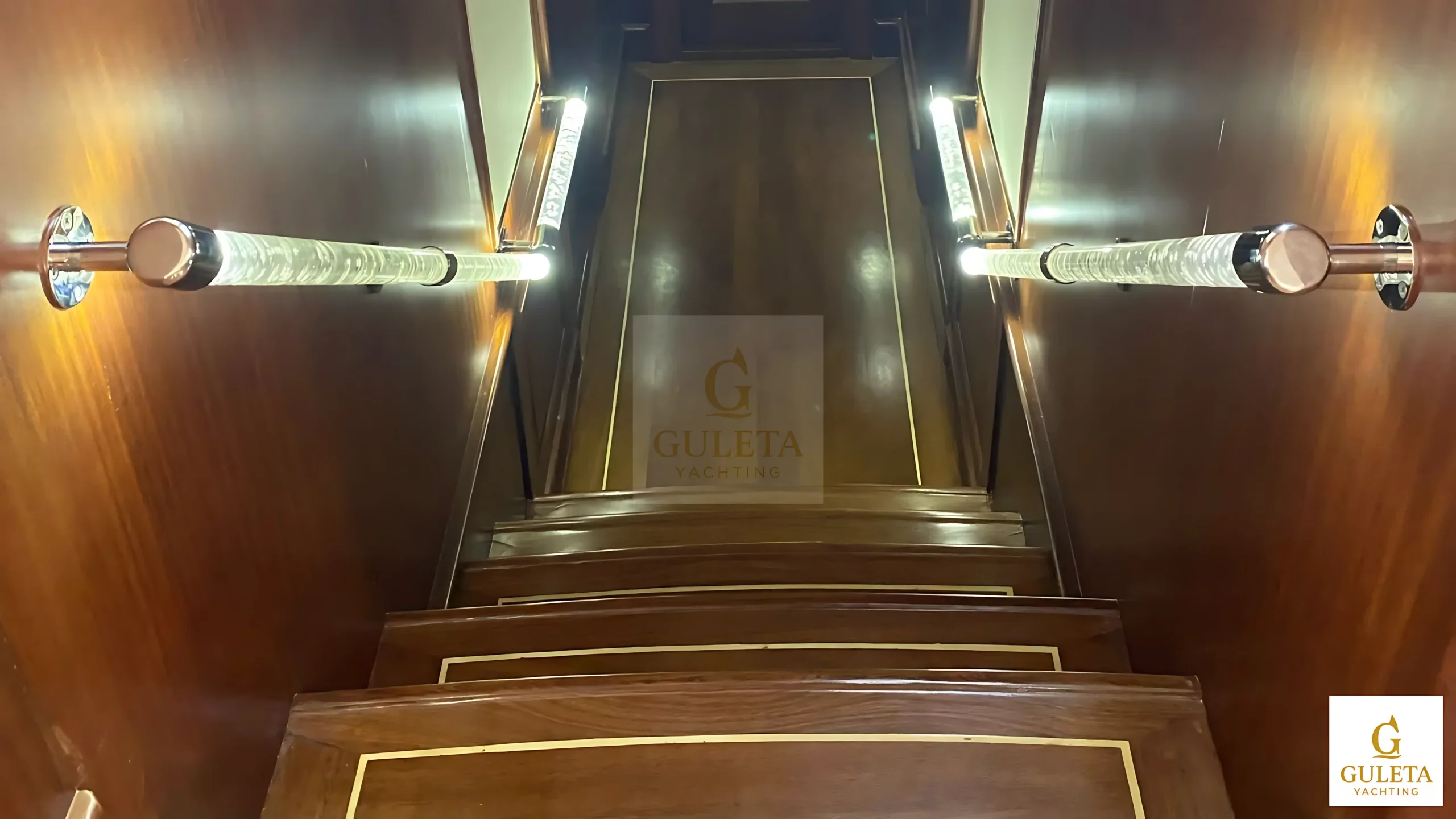 Rosa Del Mar Gulet staircase leading down to the salon, featuring polished wood and cozy interiors.