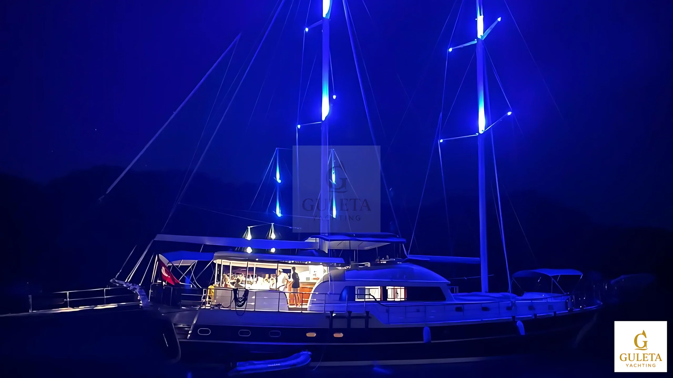 Nighttime exterior view of Sulyar Gulet illuminated against the calm coastal waters.