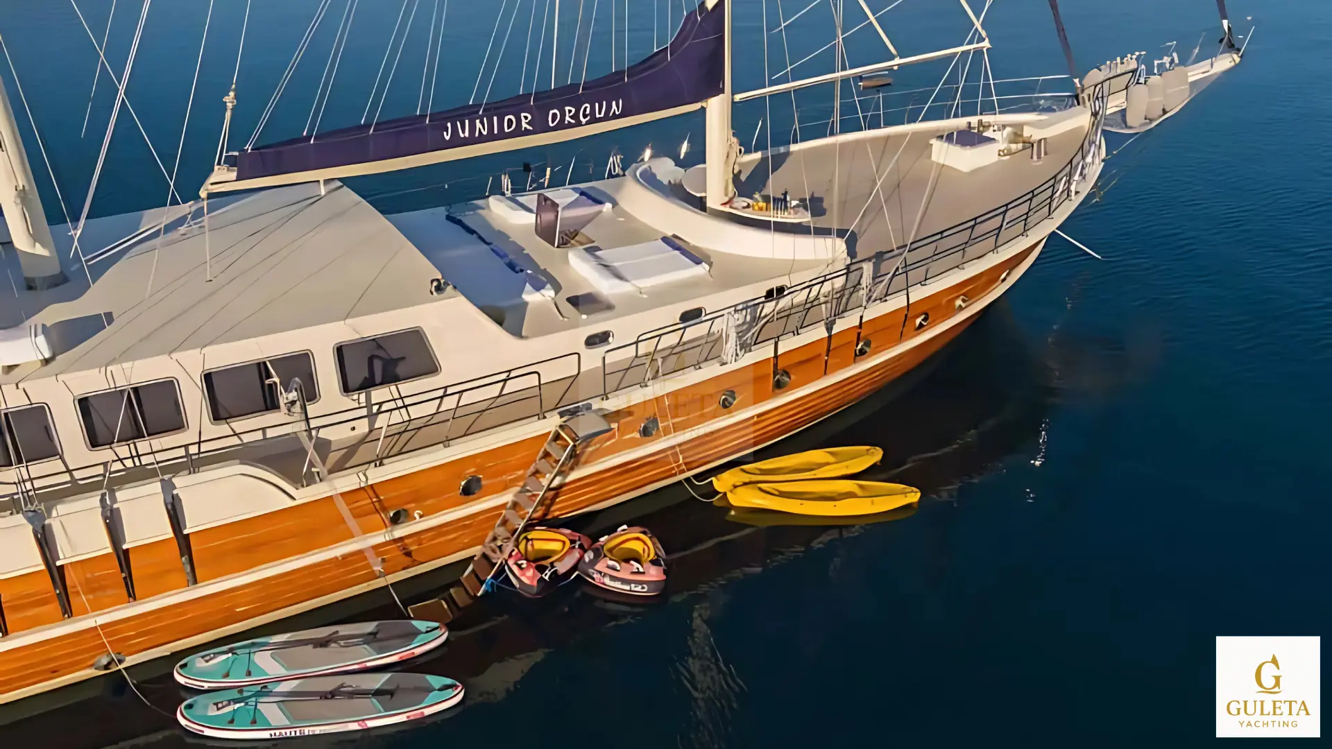 Aerial view of Junior Orcun gulet with golden duotone effect, showcasing the luxury deck and water toys - Guleta Yachting