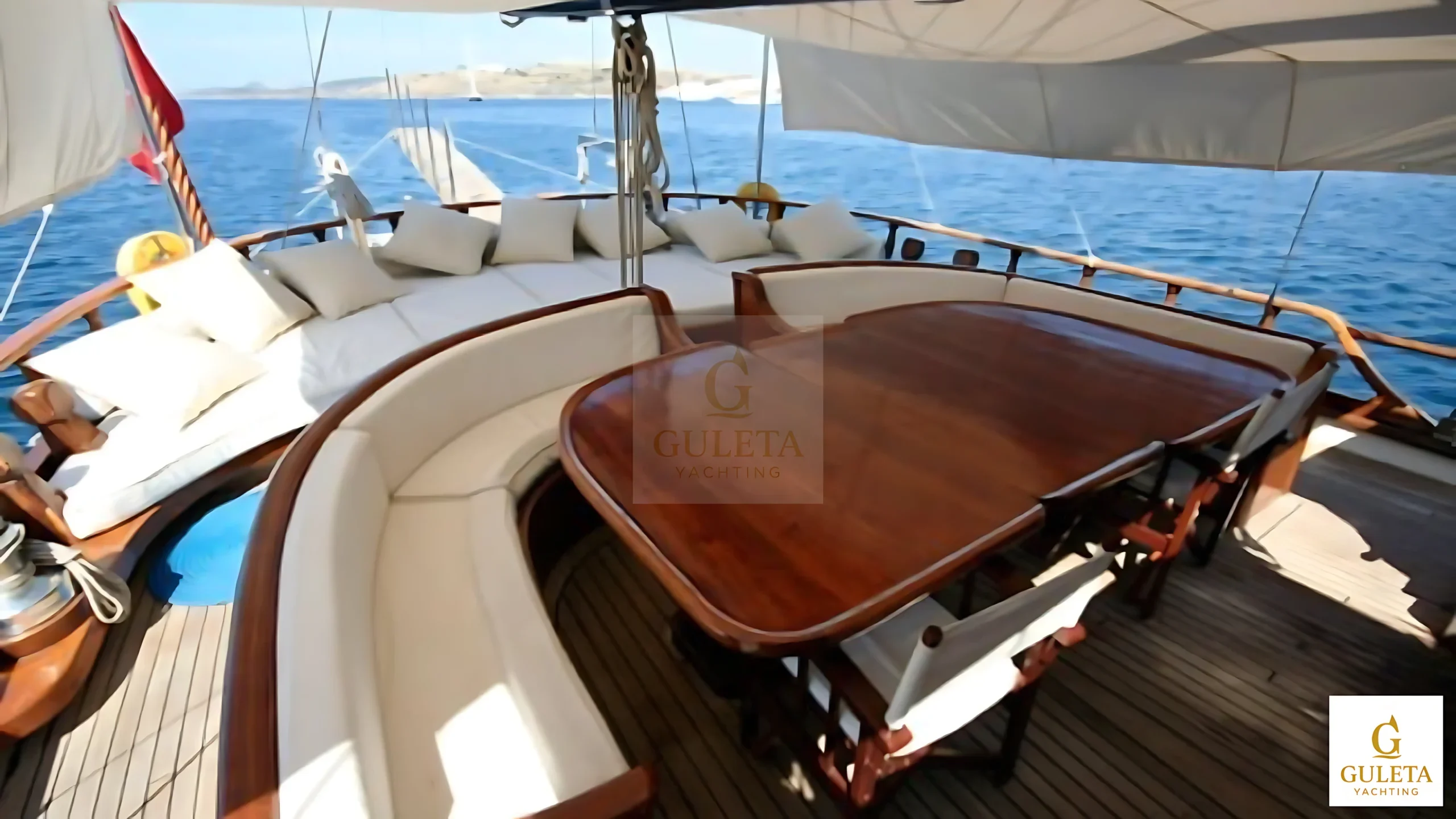 Aft deck of Kaptan Şevket Gulet with dining table and cushioned seating.